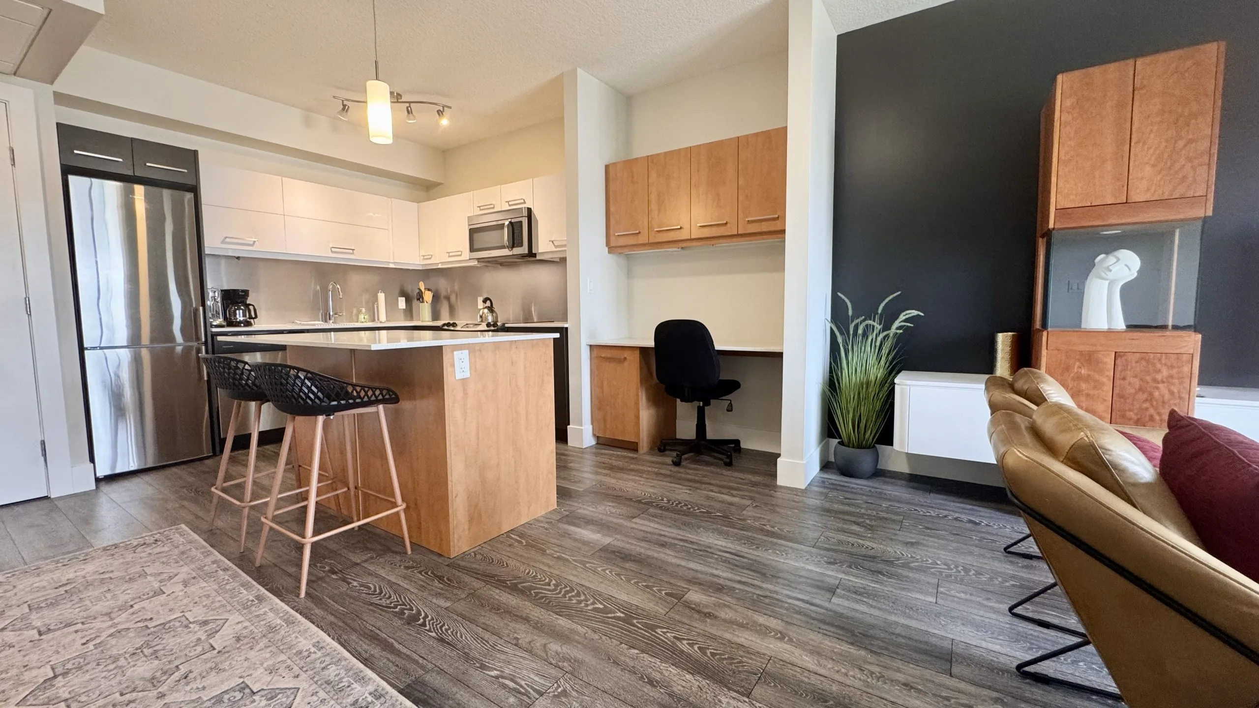 desk with office chair, counter-height chairs at island, 1-bedroom furnished suite